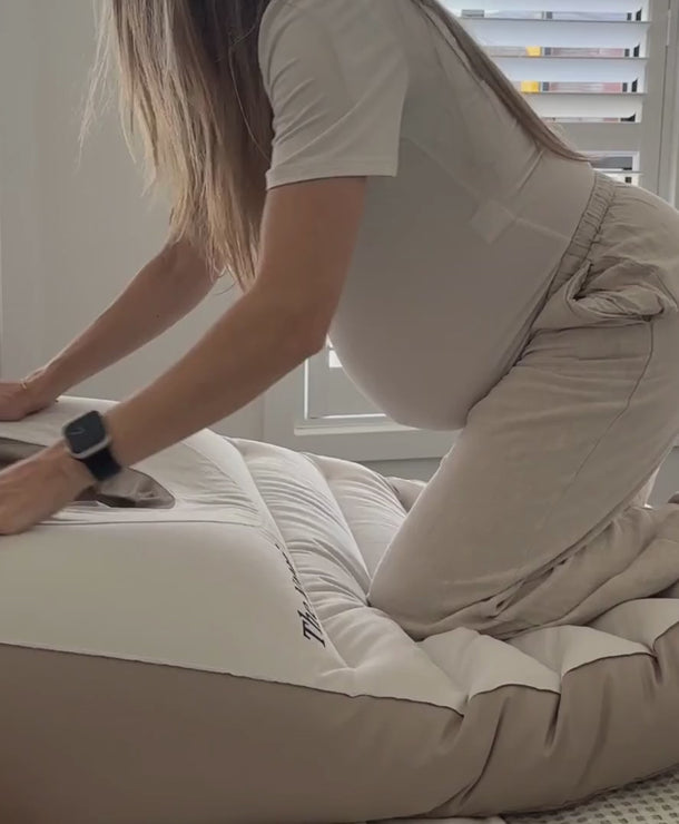 Pregnant woman lying face down using a belly sleep pregnancy pillow for comfort